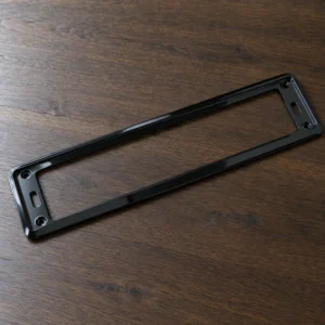 Slim gloss black number plate holder on a wooden surface